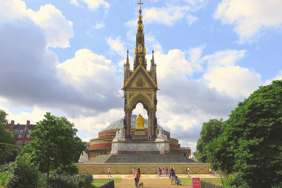 The Albert Memorial, a gold plated statue of Prince Albert, facing the Royal Albert Hall, with Hyde park trees in the background.